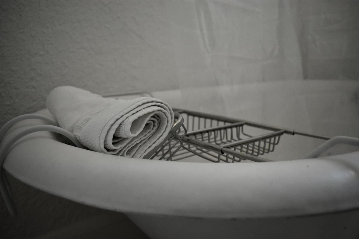 A white laundry basket with a metal wireframe inside, placed inside a white basin.
