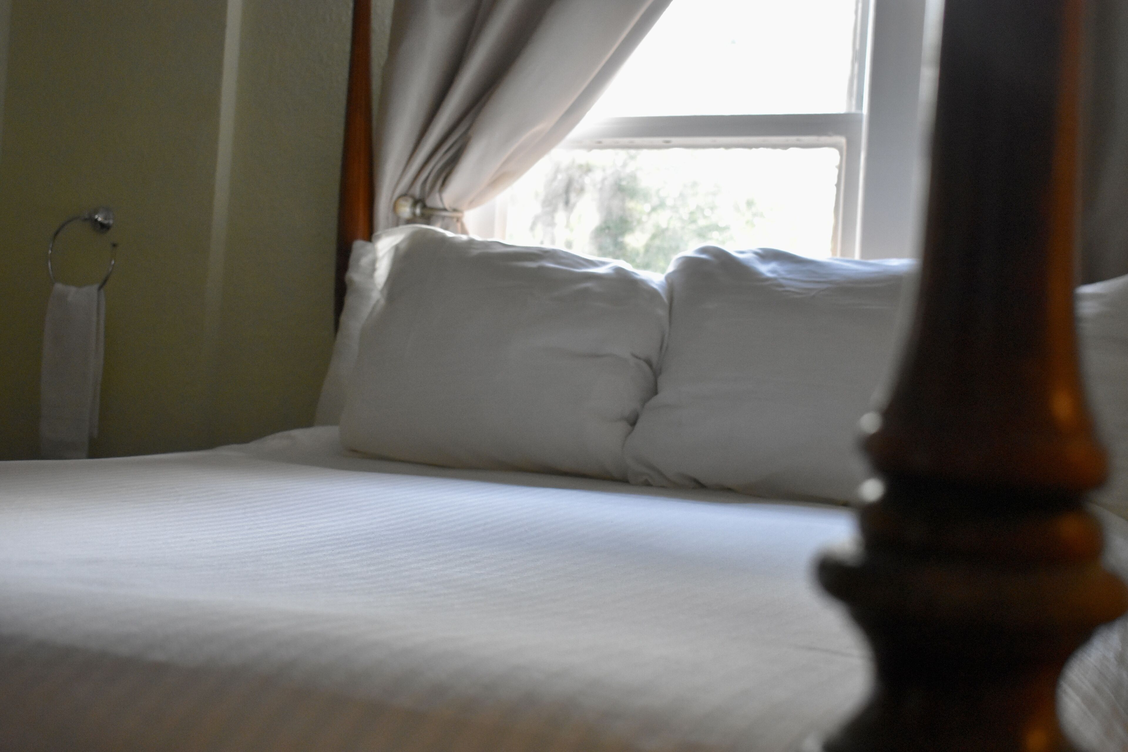 A neatly made bed with white linens and a wooden headboard.