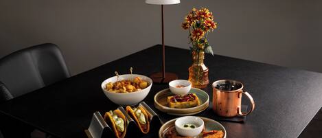 A dining table with a variety of dishes, a vase with flowers, a lamp, and a copper mug.