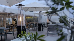 Un espacio al aire libre con mesas y sillas, sombrillas grandes y un diseño moderno.
