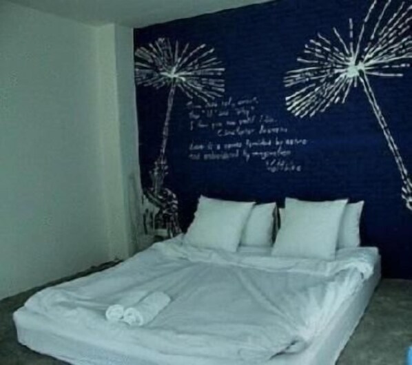 Un dormitorio con cama, almohadas y una pared con diseño decorativo.