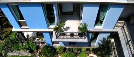 A modern building with a blue facade, multiple balconies, and a well-maintained garden area.
