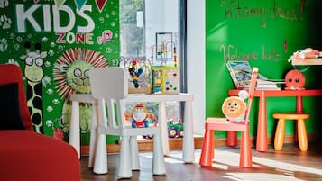 Kids can play and learn in this vibrant room with a dedicated play area featuring colorful chairs and tables.