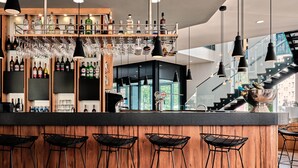 Een moderne bar met houten details, verschillende drankflessen en hangende glazen.