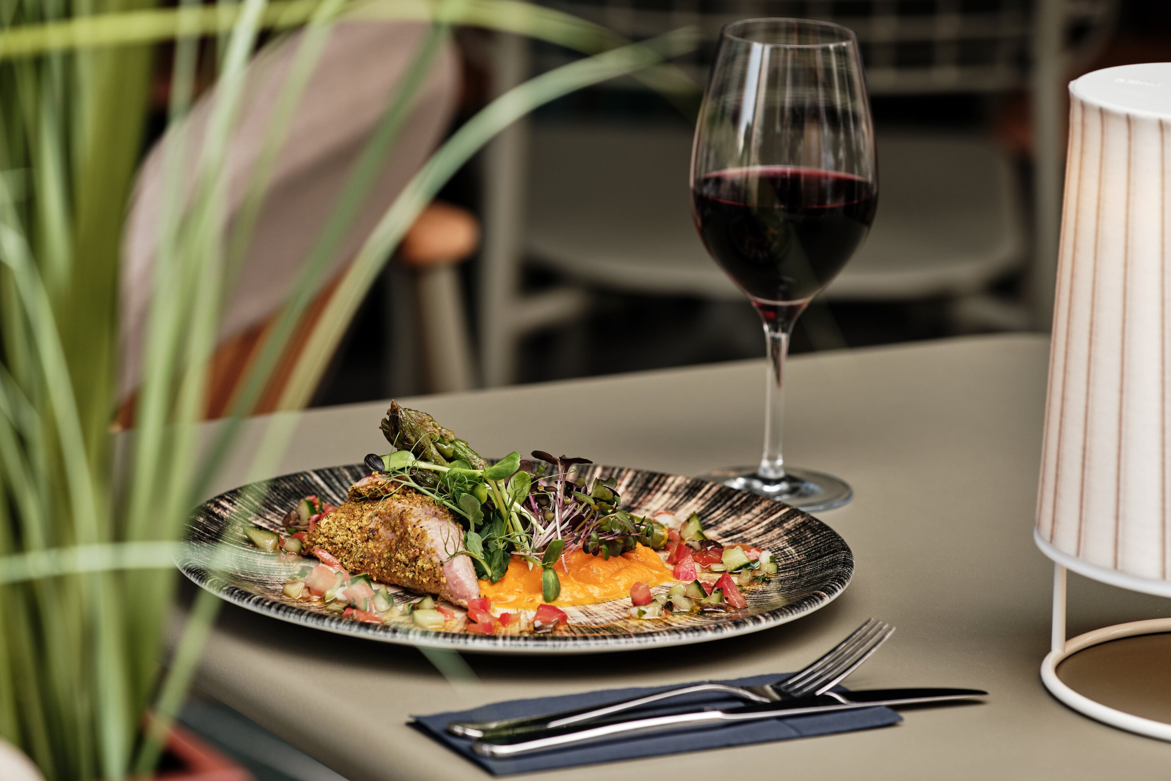 A plate of food with a glass of red wine on a table.