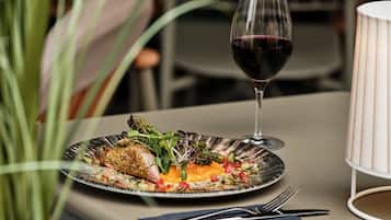 A plate of food with a glass of red wine on a table.