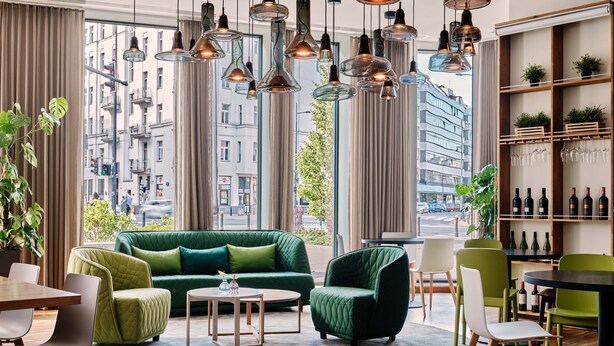 Een moderne woonkamer met een groene bank, een rond bijzettafeltje en een eethoek.