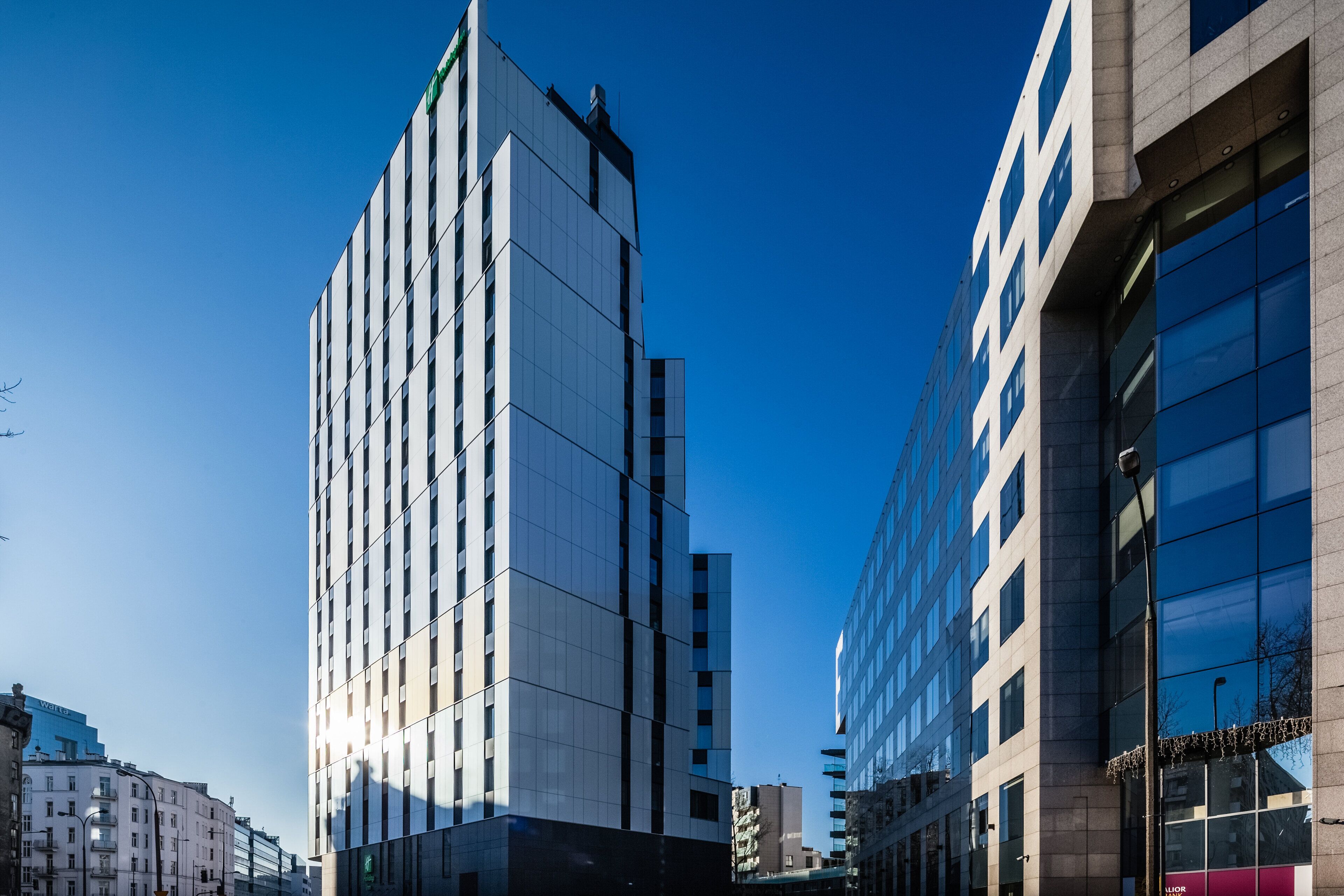 Un immeuble moderne de grande hauteur, doté d’une façade en verre réfléchissant, entouré d’autres bâtiments.