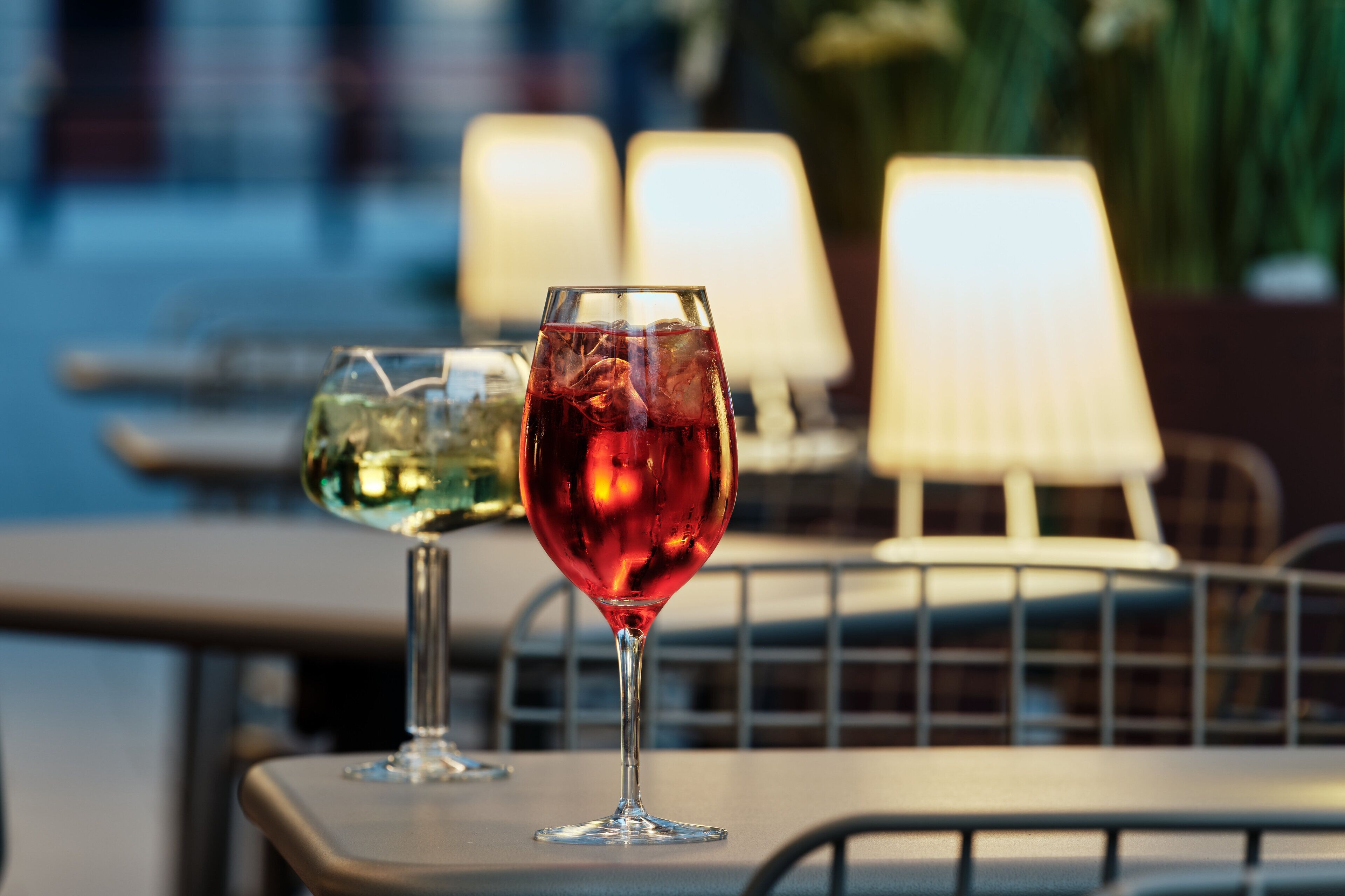 Two glasses of red wine on a table with a lamp in the background.