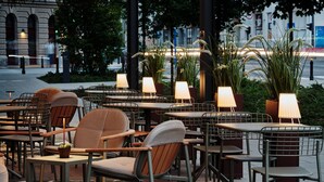 Een buitenzitplaats met tafels, stoelen, potplanten en lampen.