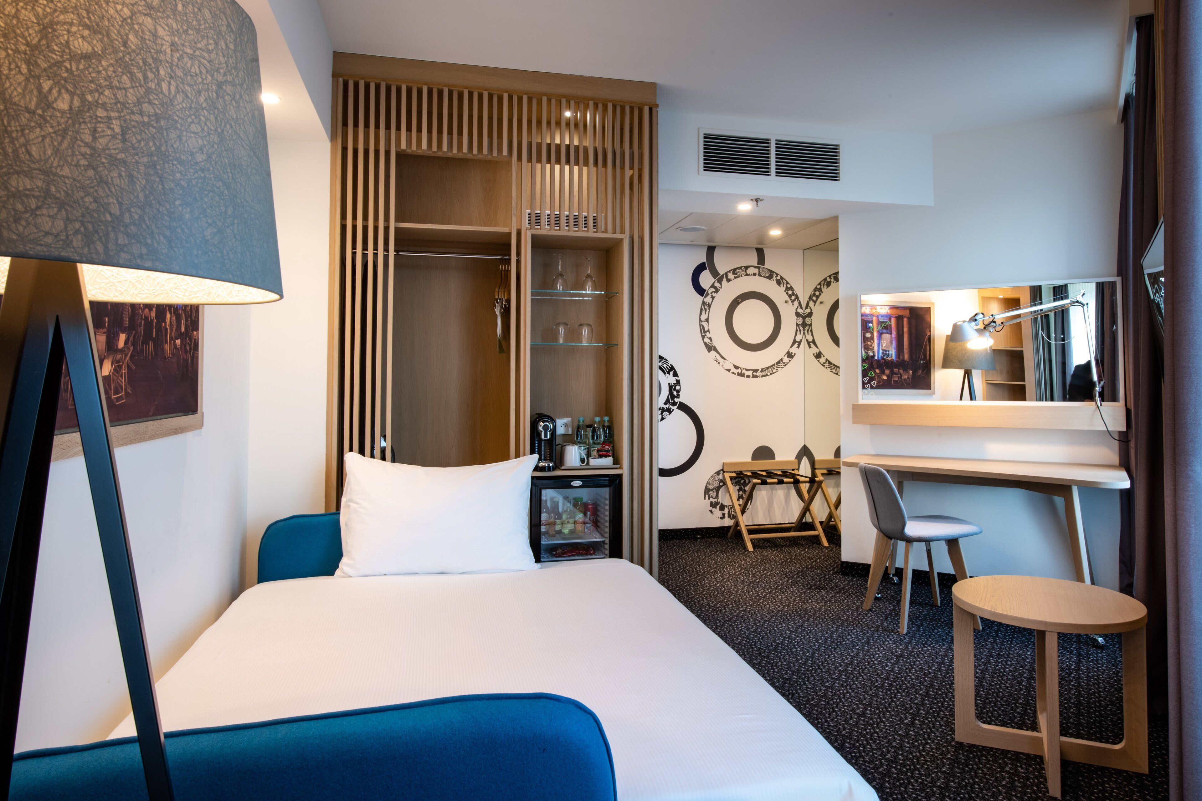 Ein Hotelzimmer mit einem Bett, einem Schreibtisch, einem Stuhl, einem Kleiderschrank und einem Spiegel.