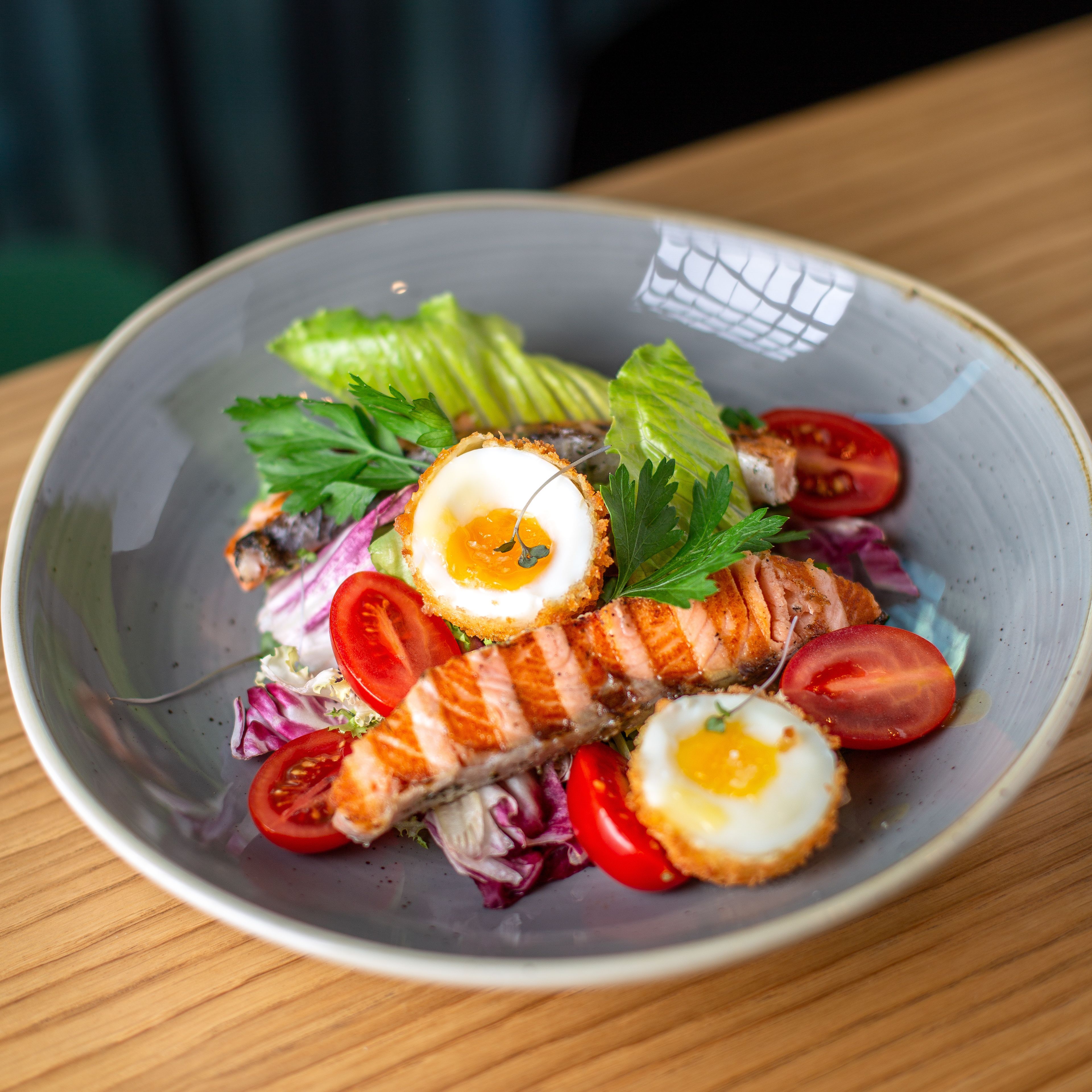 A plate of food with salmon, eggs, and vegetables.