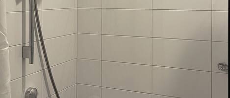 A modern shower with a handheld showerhead, a fixed showerhead, and a handheld shower attachment.