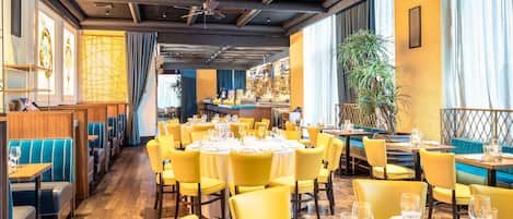 Un restaurante con sillas y mesas amarillas, pisos de madera y un ventilador de techo.