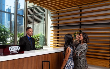 A reception desk with a sign reading "pod express checkout" in a modern building with large windows and wooden slats on the wall.
