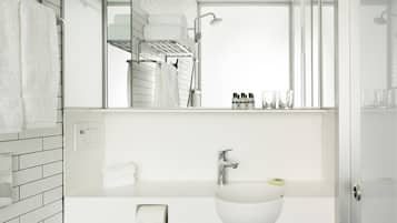 Un baño moderno con un lavamanos blanco, espejo y paredes con azulejos.