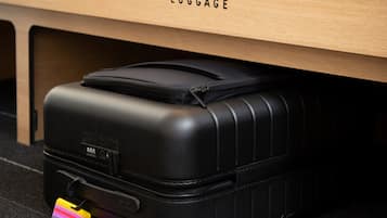 Una maleta negra con un cartel colorido debajo de un escritorio de madera que dice 'LUGGAGE'.
