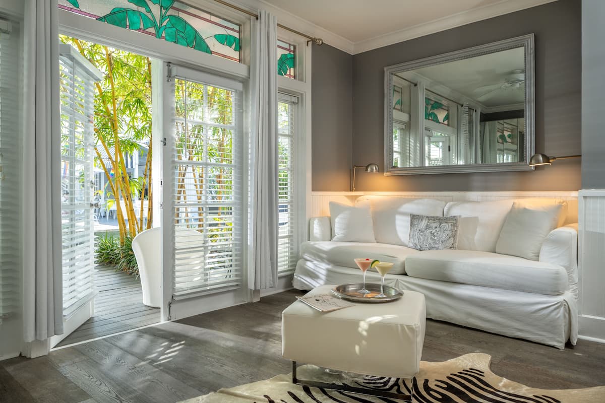 A modern hotel room with a white sofa, a zebra-patterned rug, and a large mirror above the sofa.