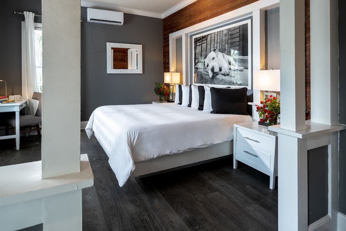 A modern bedroom with a large bed, bedside tables, a desk, and a window with a view.
