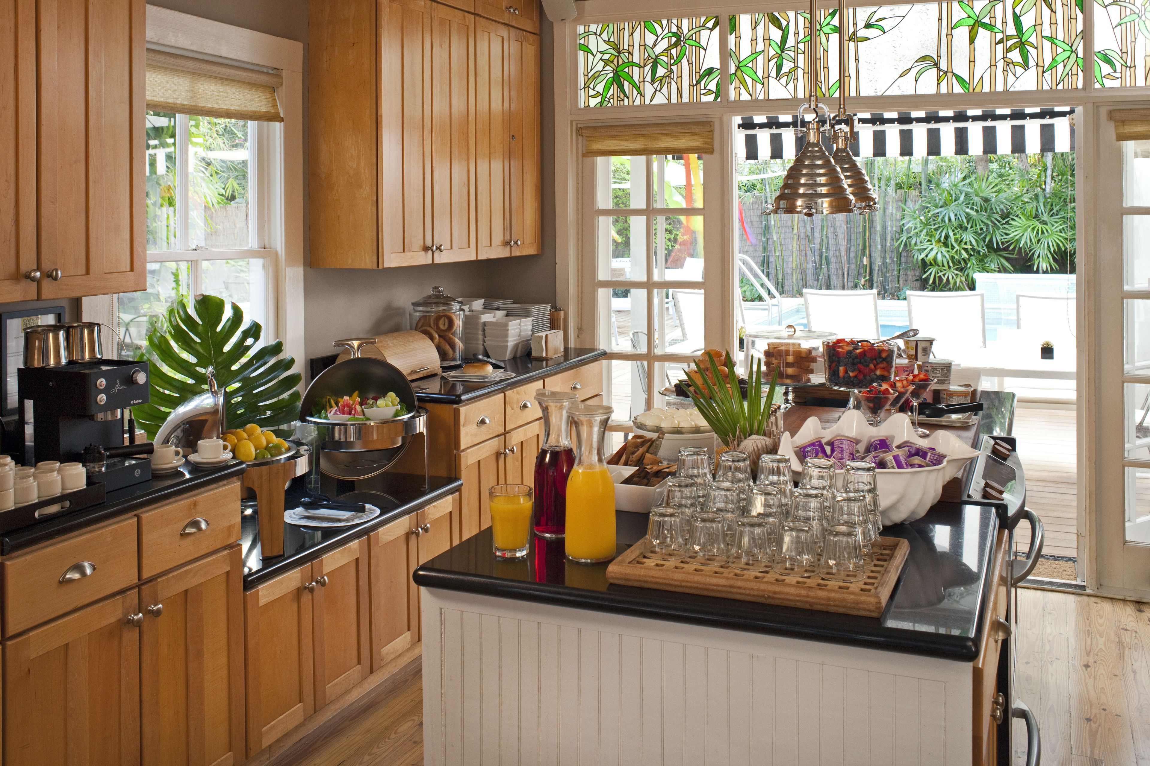 Una cocina con armarios de madera, encimera negra y una barra de desayuno con diversos alimentos y bebidas.