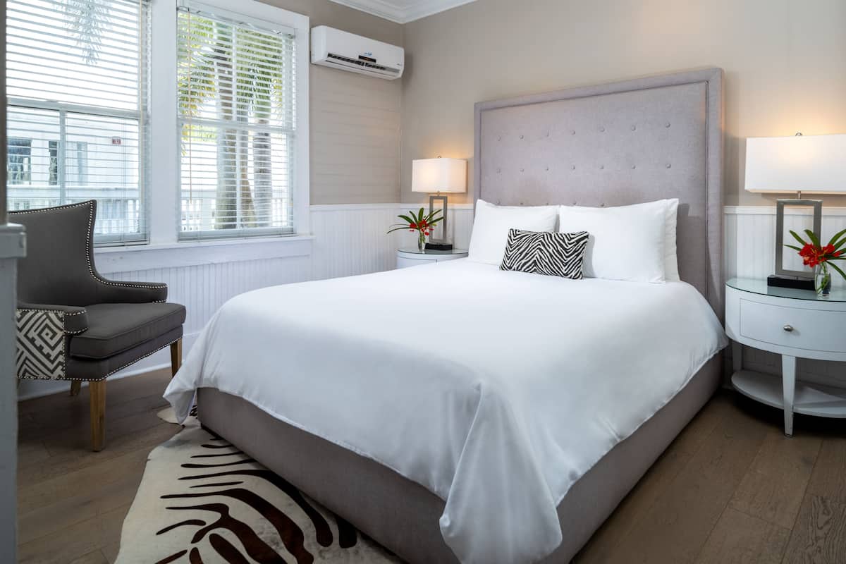A neatly arranged bedroom with a large bed, two bedside tables with lamps, a chair, and a zebra-patterned rug.
