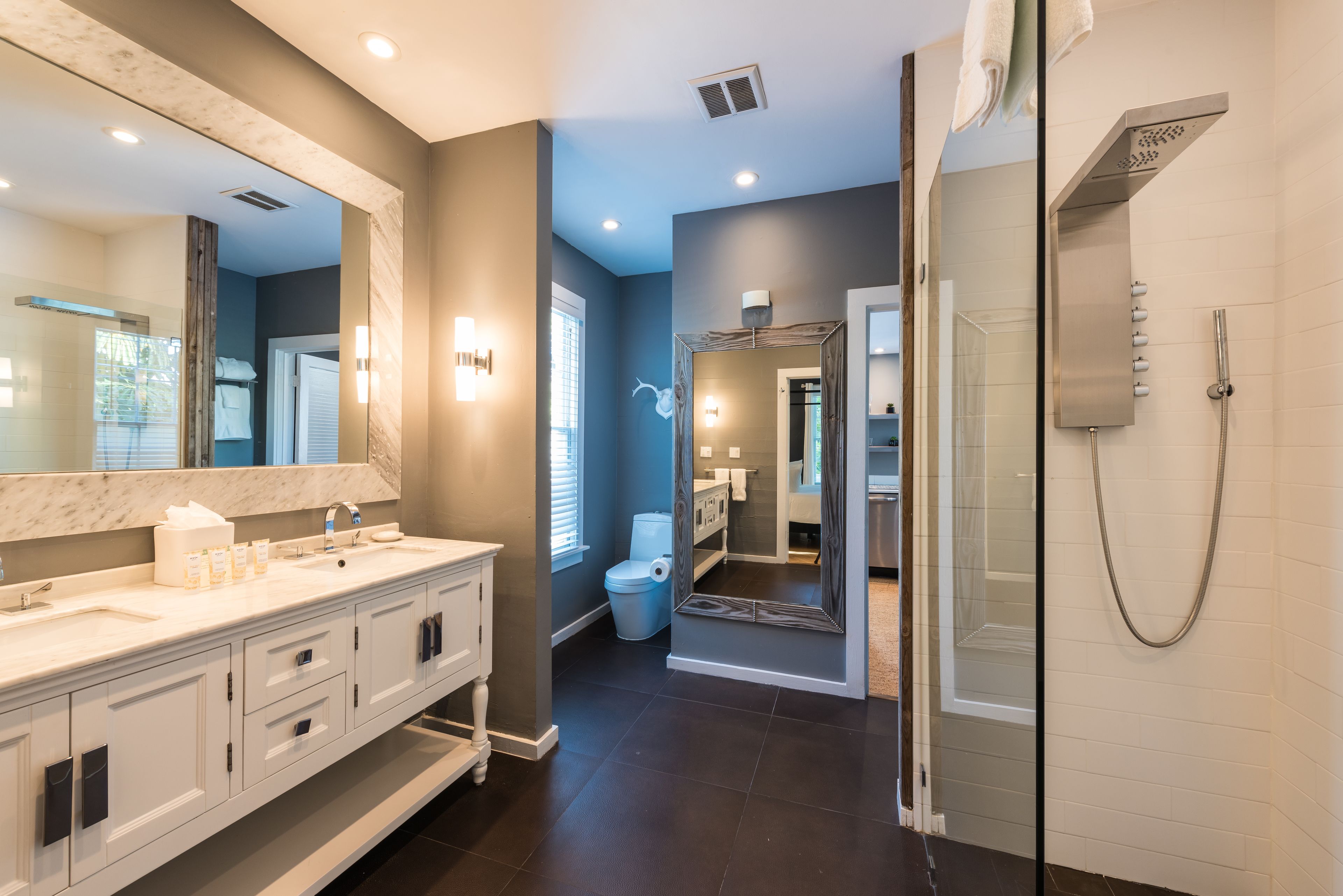 Une salle de bain moderne dotée d’un grand miroir, de deux vasques, d’une douche et d’une douche à l’italienne avec parois en verre.