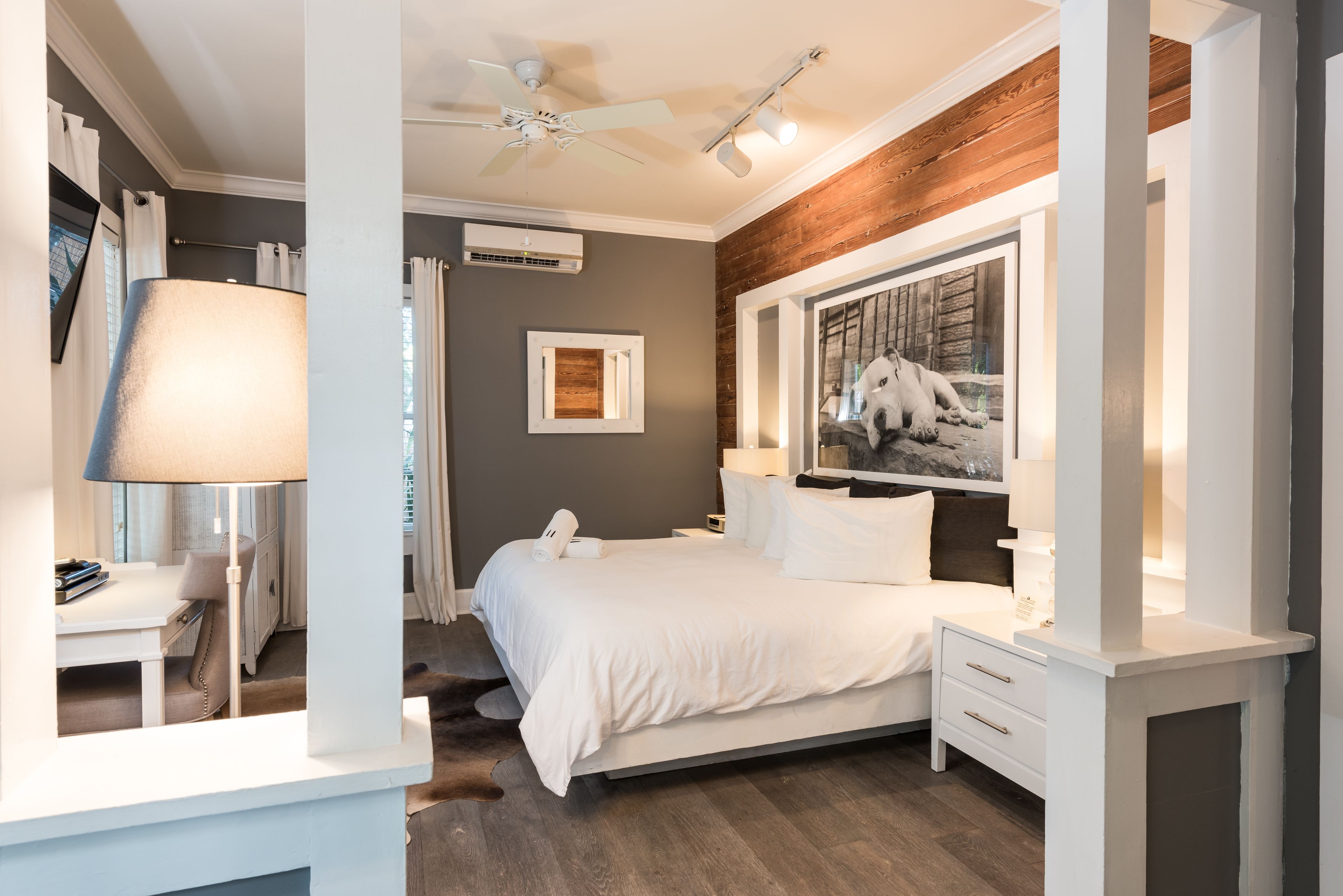 Un dormitorio moderno con una cama grande, un ventilador de techo y un cuadro en la pared.