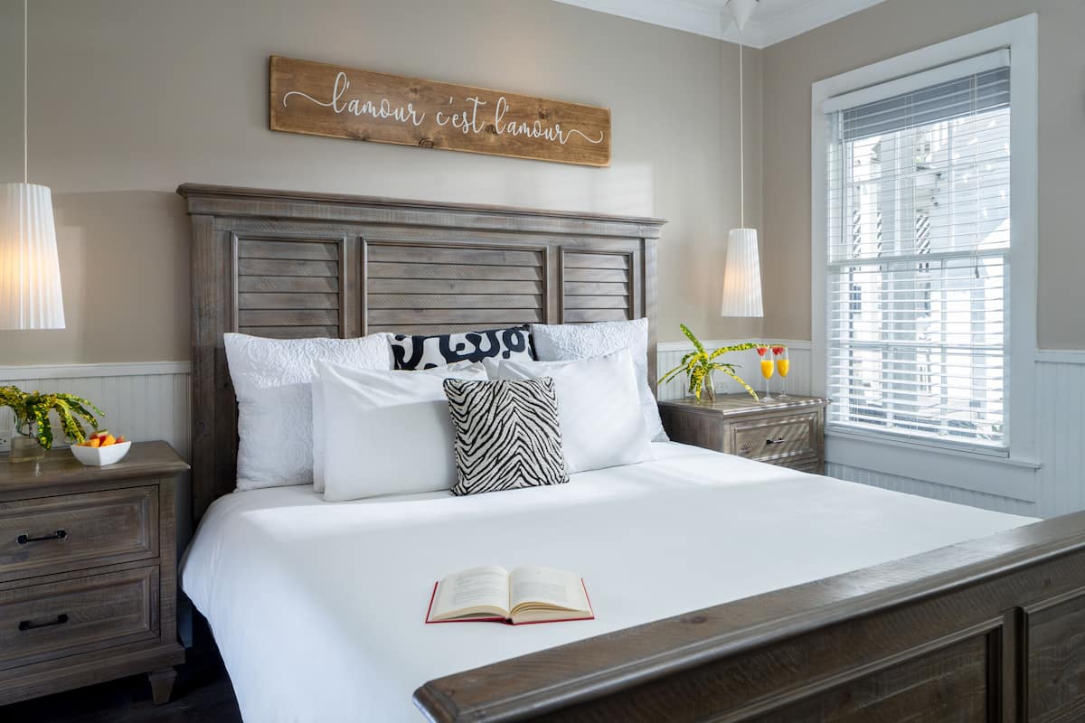 A neatly made bed with a book, a wooden headboard, and a wall sign.