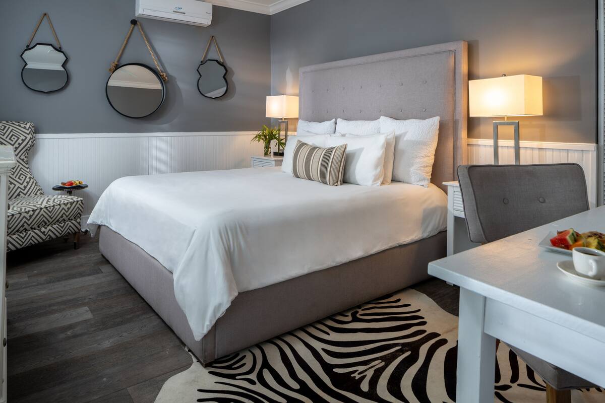 A modern hotel room with a large bed, a dining table, and a zebra-patterned rug.