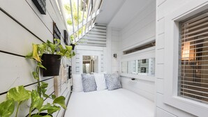 Una habitación estrecha con una cama, una planta en maceta y una ventana con persianas.