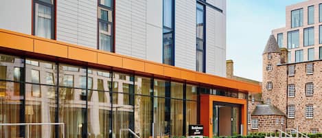 A modern hotel with a glass facade, a stone tower, and a sign reading "Residence Inn."