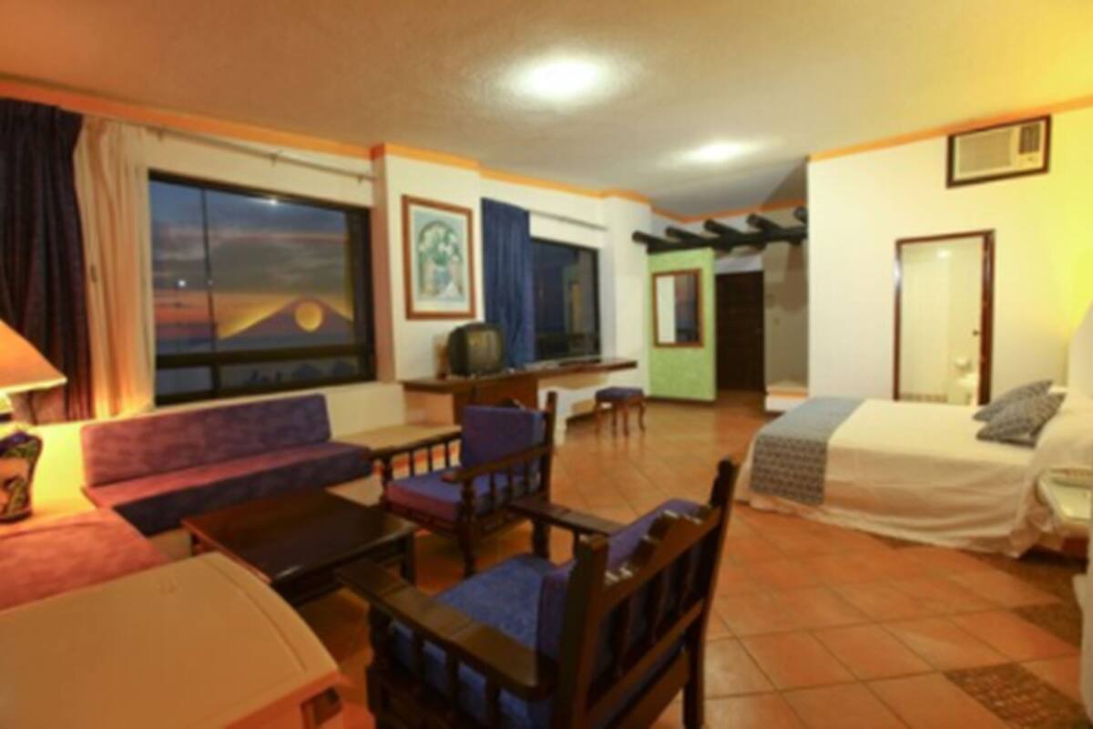 Ett hotellrum med ett stort fönster, en soffa, en säng, ett skrivbord och en stol.