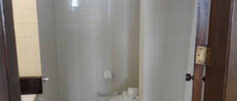 A small, narrow bathroom with white tiles, a toilet, and a sink.