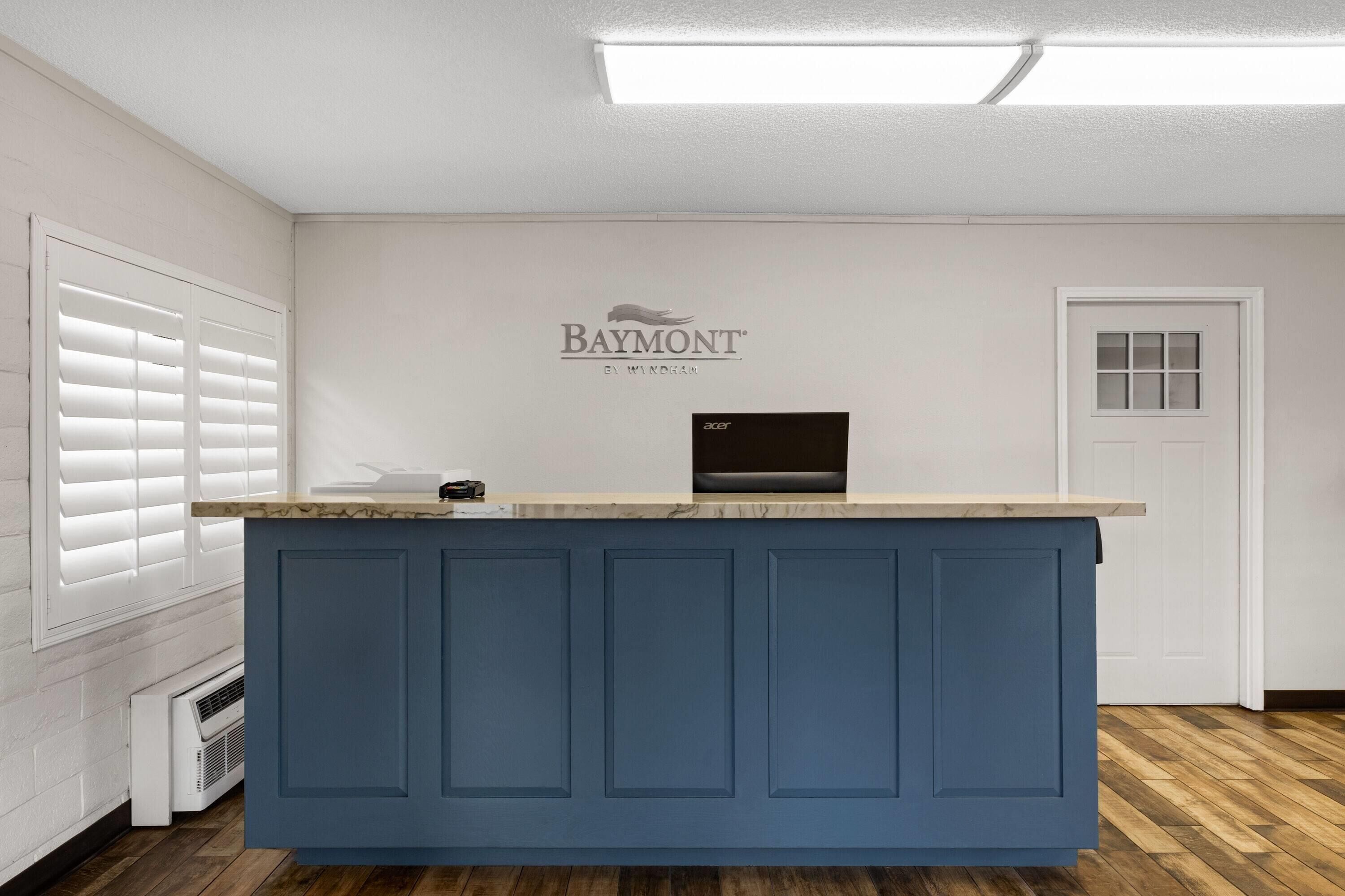 Um balcão de recepção com painel azul, o logotipo Baymont e um monitor Acer.
