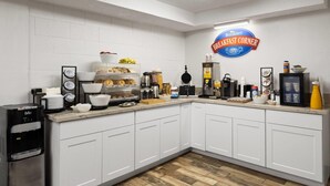 Uma mesa de pequeno-almoço com o letreiro Baymont, uma máquina de café e diversas opções para o pequeno-almoço.