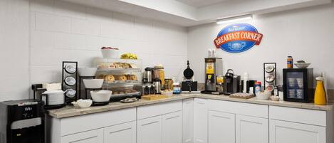 Una barra de desayuno con un letrero de Baymont, una máquina de café y diversos alimentos para el desayuno.