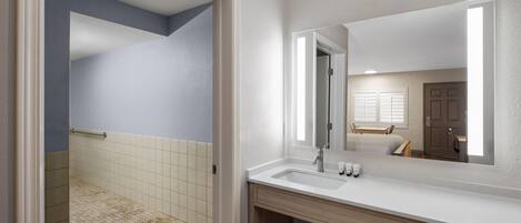 A modern bathroom with a large mirror, a sink, and a shower area.