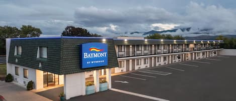 A Baymont by Wyndham hotel with a parking lot and a mountain backdrop.