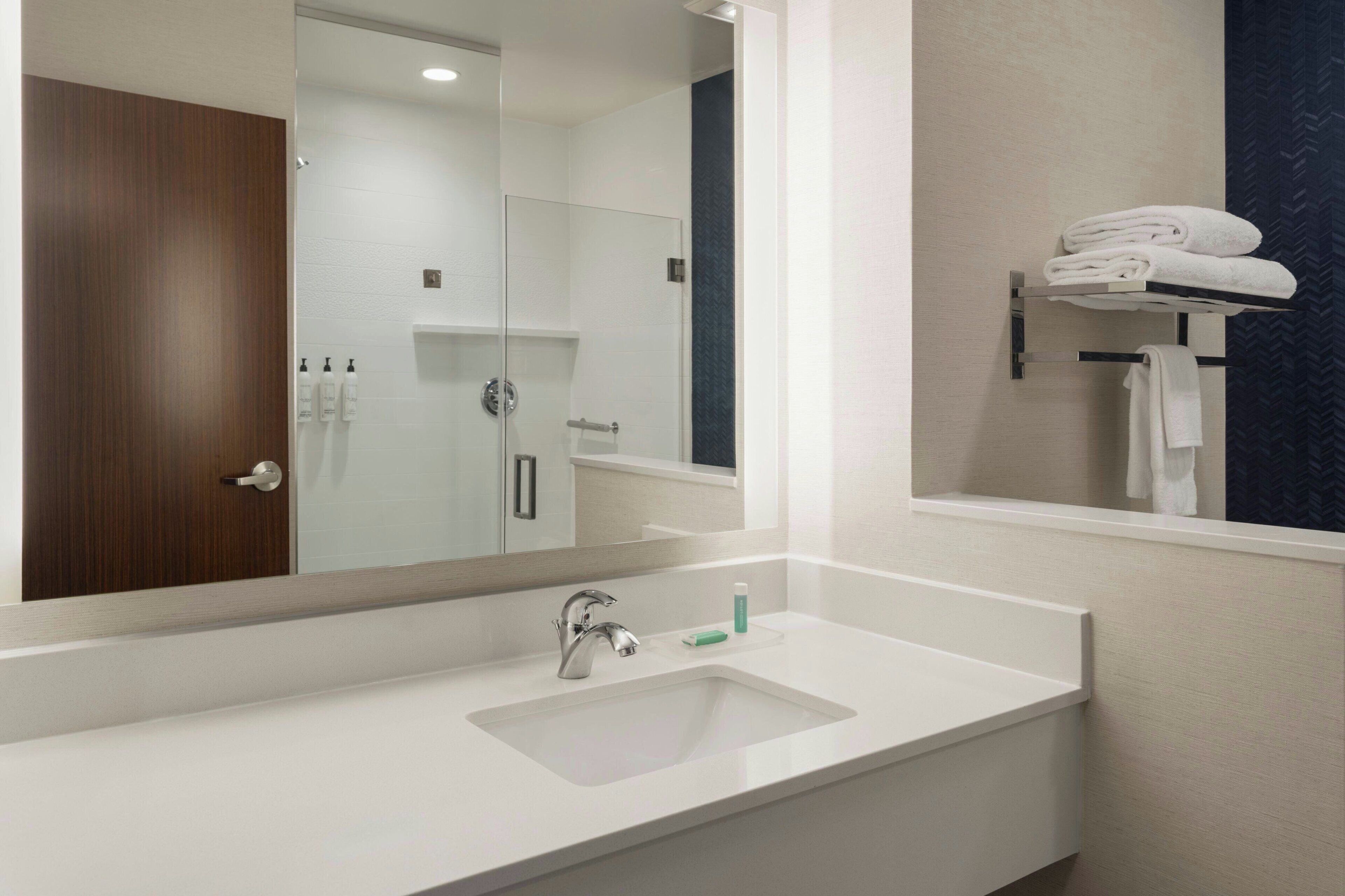 A modern bathroom with a white sink, a mirror, and a towel rack.