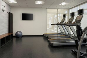 A gym with treadmills, a stationary bike, a rowing machine, a large exercise ball, and a TV on the wall. - Fairfield Inn & Suites by Marriott Indianapolis Fishers (Indianapolis)