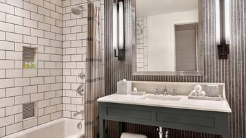A modern bathroom with white subway tiles, a bathtub, a vanity with a mirror, and striped wallpaper.