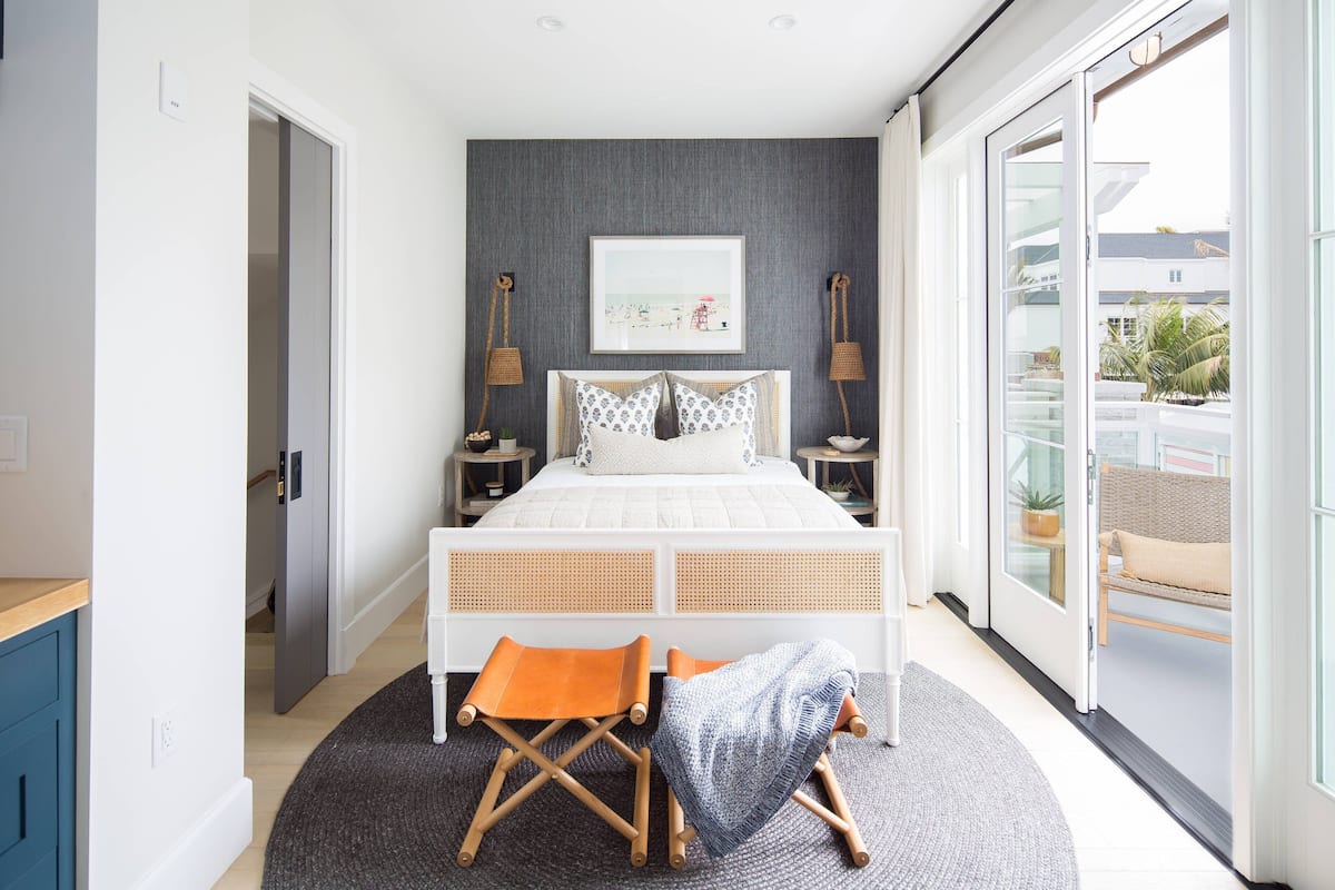 A modern bedroom with a large bed, a small seating area, and a view of the outdoors.