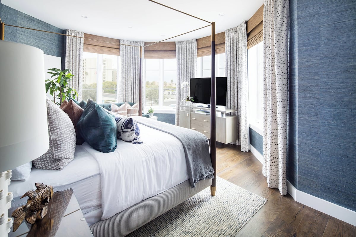 A modern bedroom with a large bed, a TV, and a view of the city.