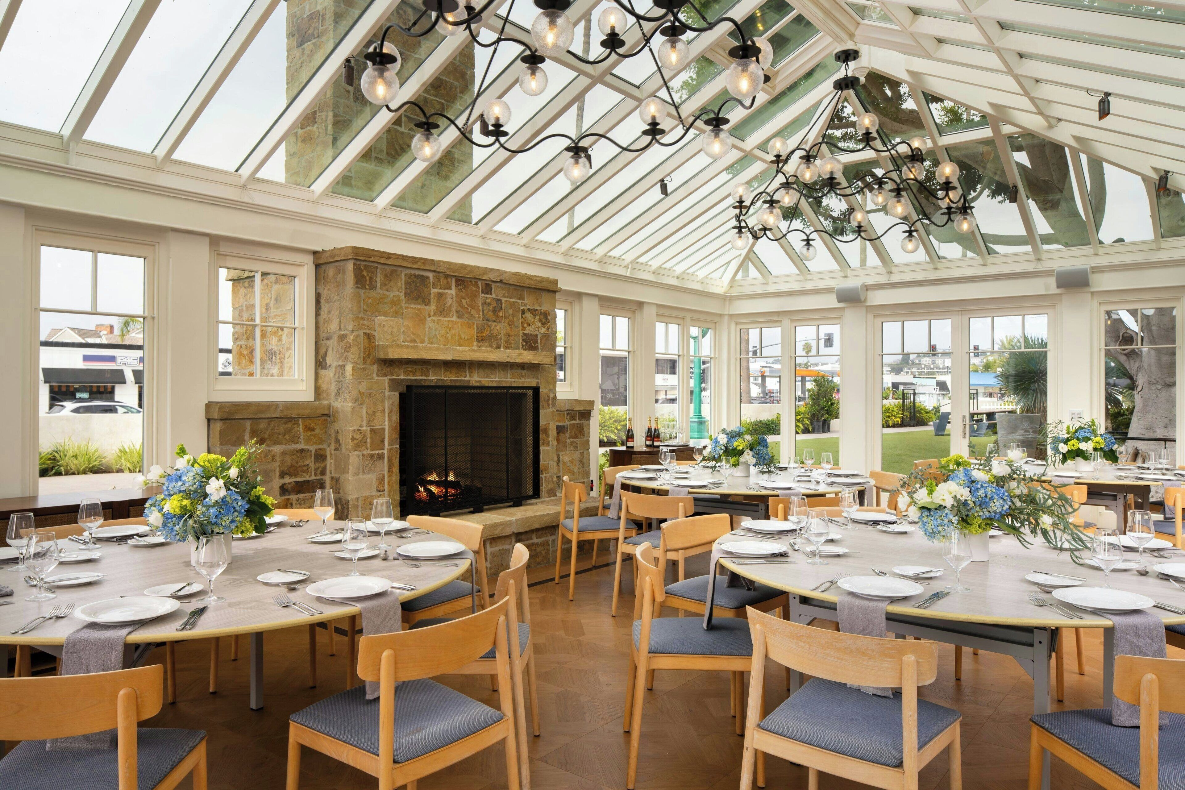 Un restaurant doté d’une cheminée en pierre, de tables et de chaises en bois, et d’un plafond en verre.