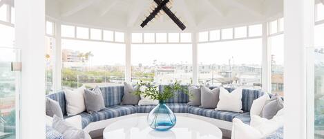 A modern, open-plan living area with a round white coffee table, a blue vase, and a blue and white patterned sofa set.