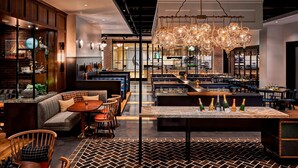 Ein modernes Restaurant mit Barbereich, Sitzgelegenheiten und einem markanten Kronleuchter.