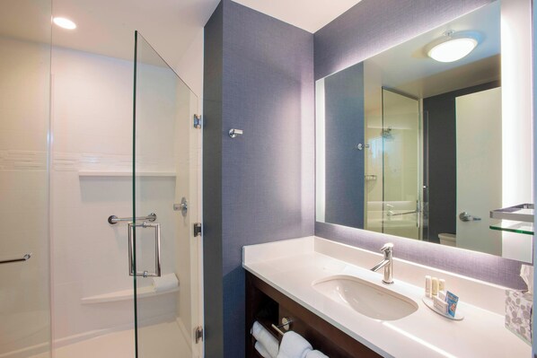 Un baño moderno con cabina de ducha de vidrio, un lavabo blanco y un espejo grande.