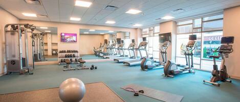 A gym with treadmills, elliptical machines, and free weights.