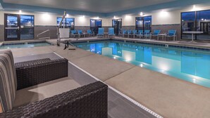 A pool area with lounge chairs and a small table, surrounded by windows.