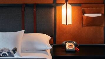 A hotel room with a bed, a nightstand, a telephone, and a wall-mounted light fixture.